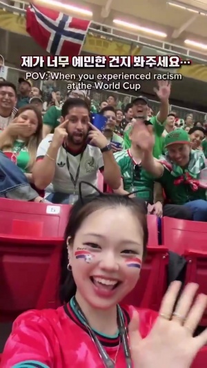 韩国球迷博主看台自拍，墨西哥球迷背后比出拉眼角手势